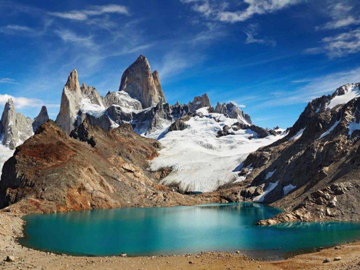 A hiker overlooking sharp, snow-capped peaks in Patagonia